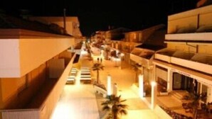 Un couloir d’hôtel donnant accès à de nombreuses chambres, un espace piscine et un bar.