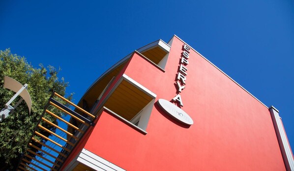 A red building with a sign reading "HOTEL" and a balcony.