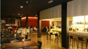 Un restaurant moderne doté d’un bar, de plusieurs tables et d’un éclairage d’ambiance chaleureux.