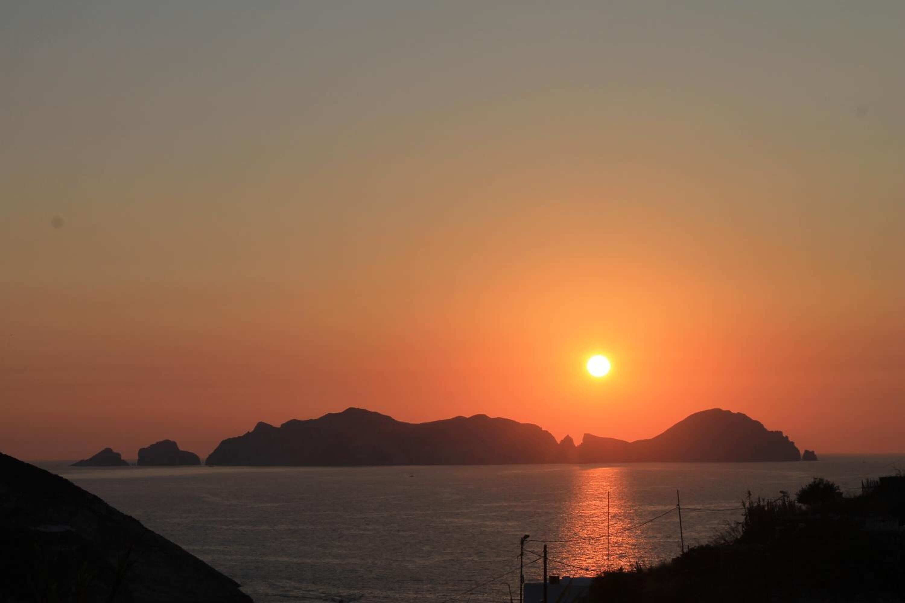 Solnedgang over et roligt hav med fjerne landskaber.