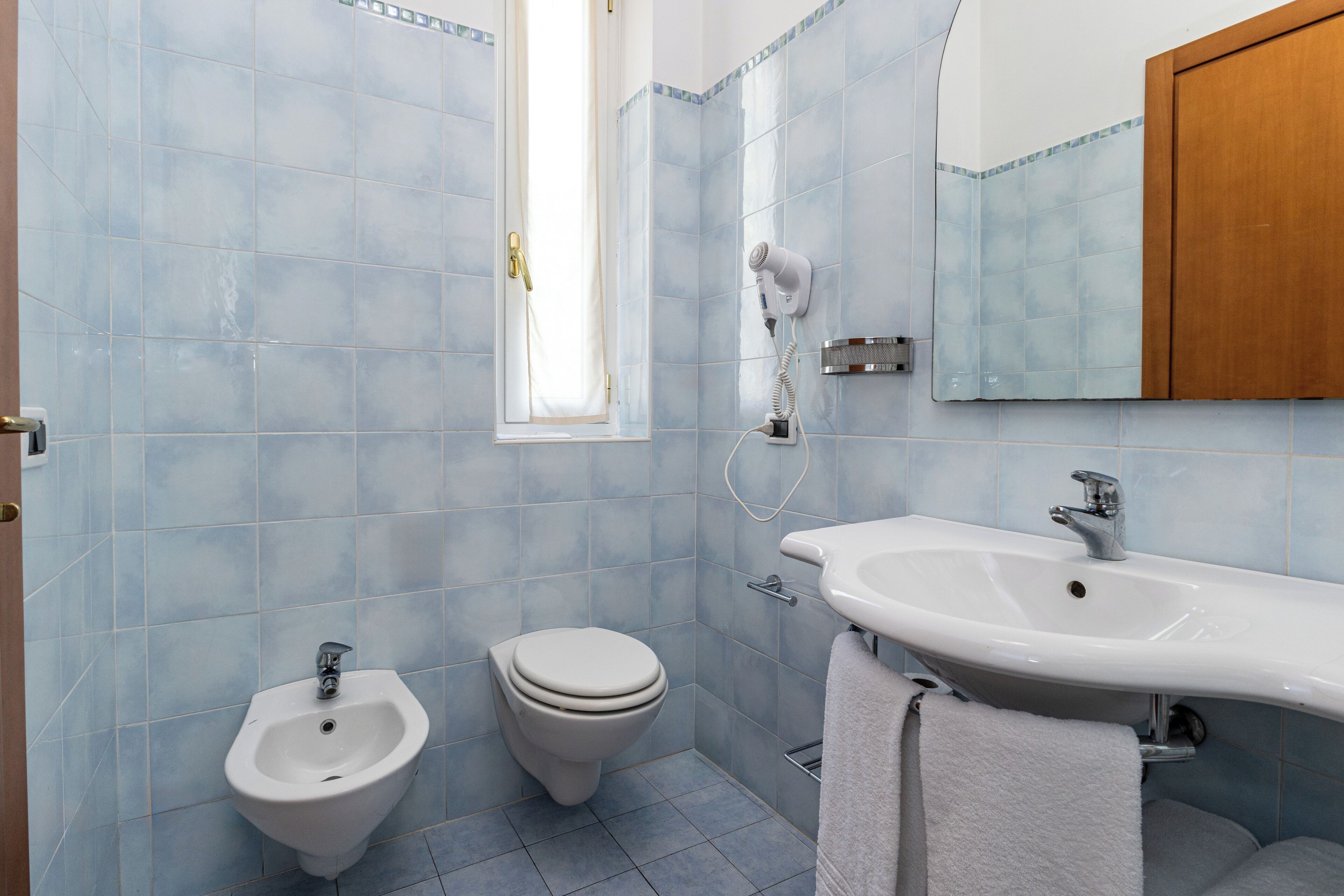 Un baño con bidé, inodoro, lavabo y espejo.