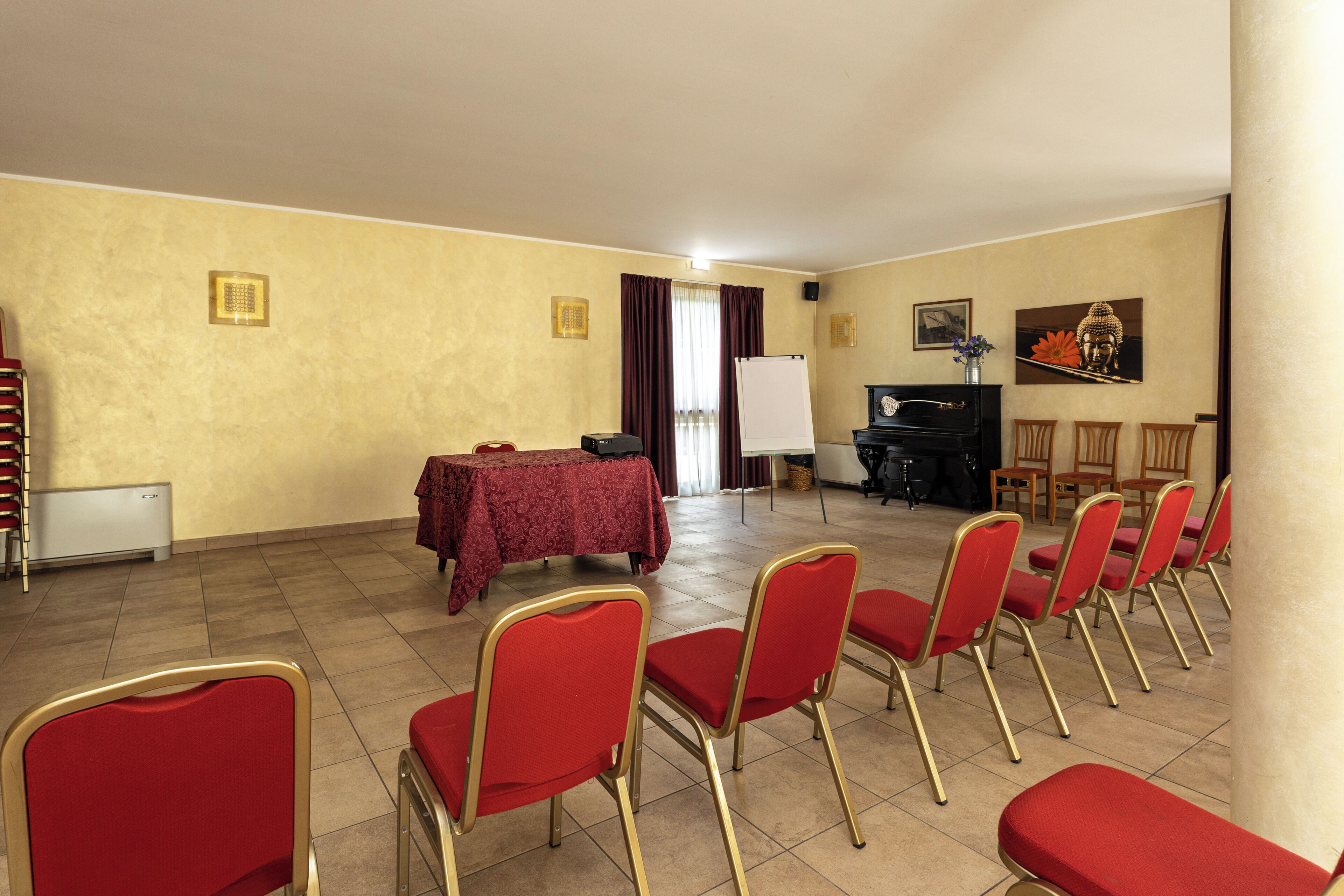 A conference room with a whiteboard, a piano, and red chairs arranged for a meeting.