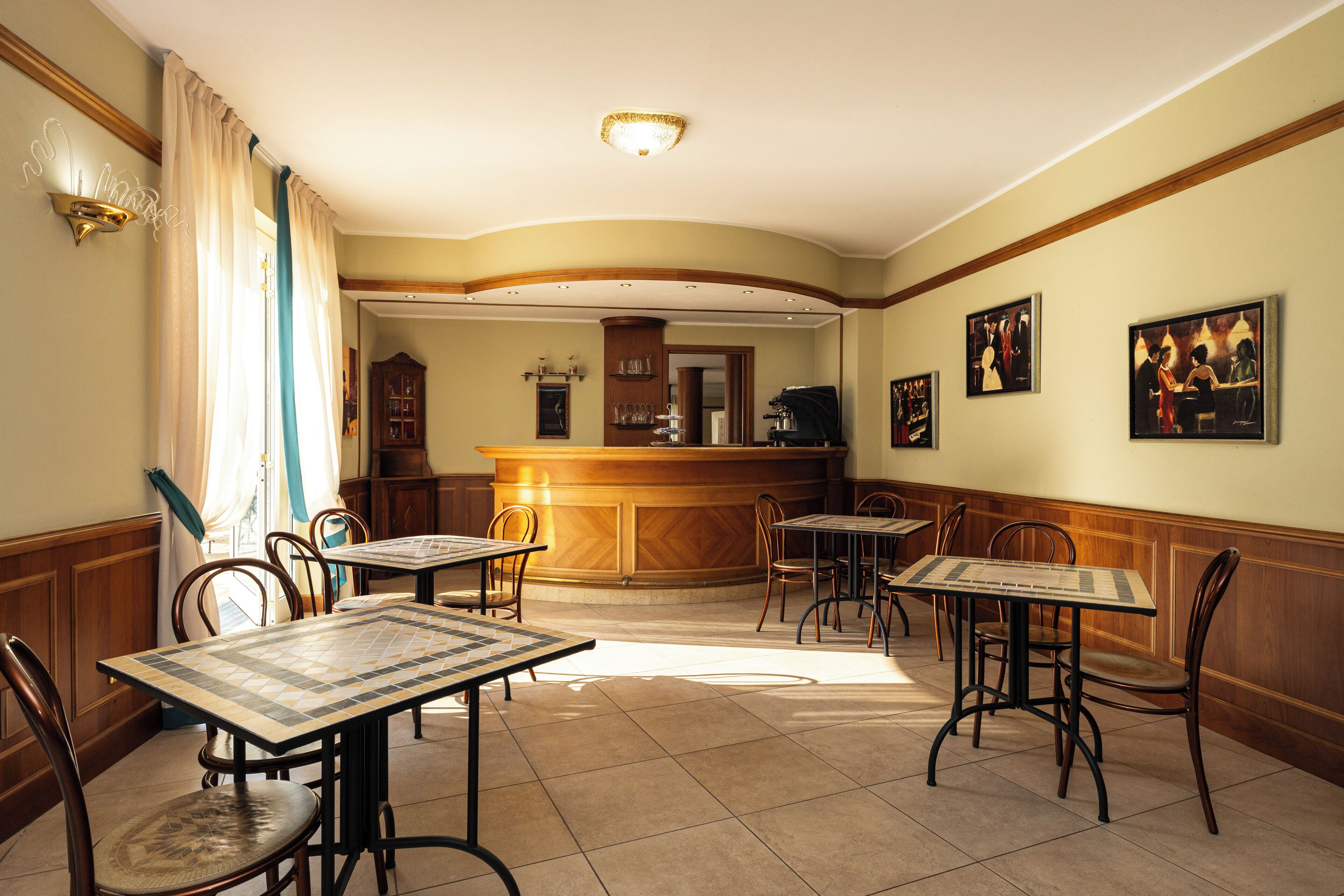 Un espace repas avec des tables et des chaises, un bar et des tableaux encadrés accrochés au mur.