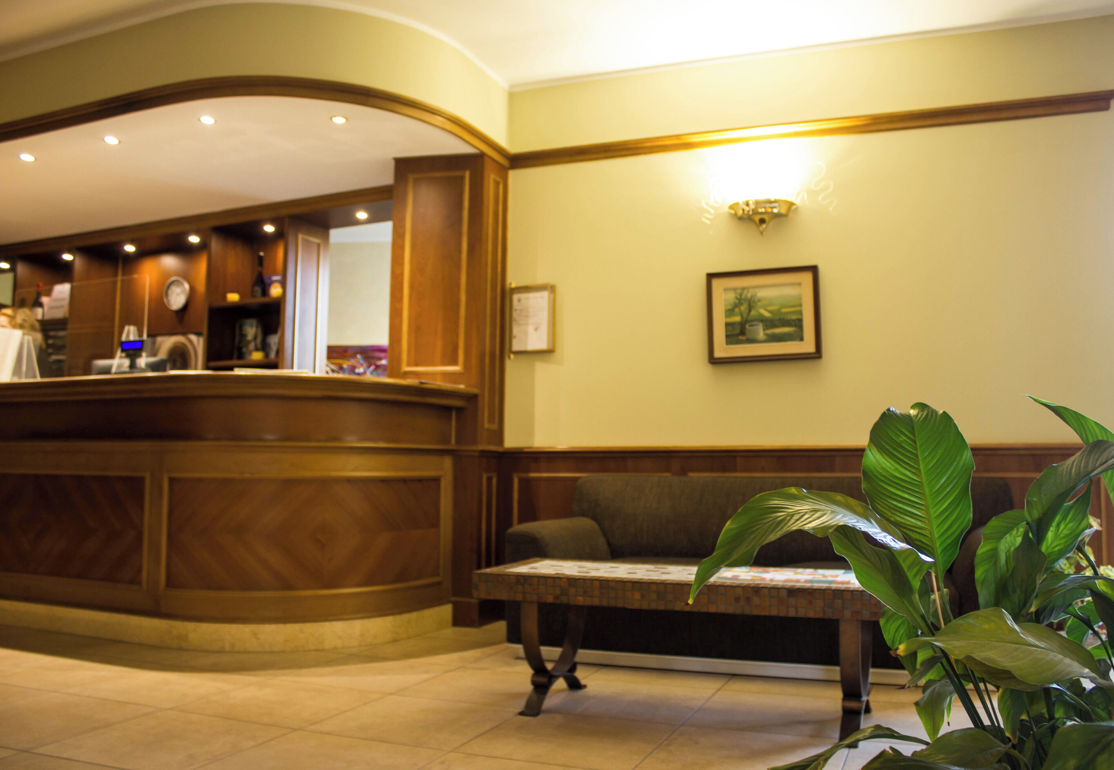 A reception area with a wooden reception desk, a bench, and a wall-mounted light fixture.