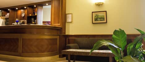 A reception area with a wooden reception desk, a bench, and a wall-mounted light fixture.