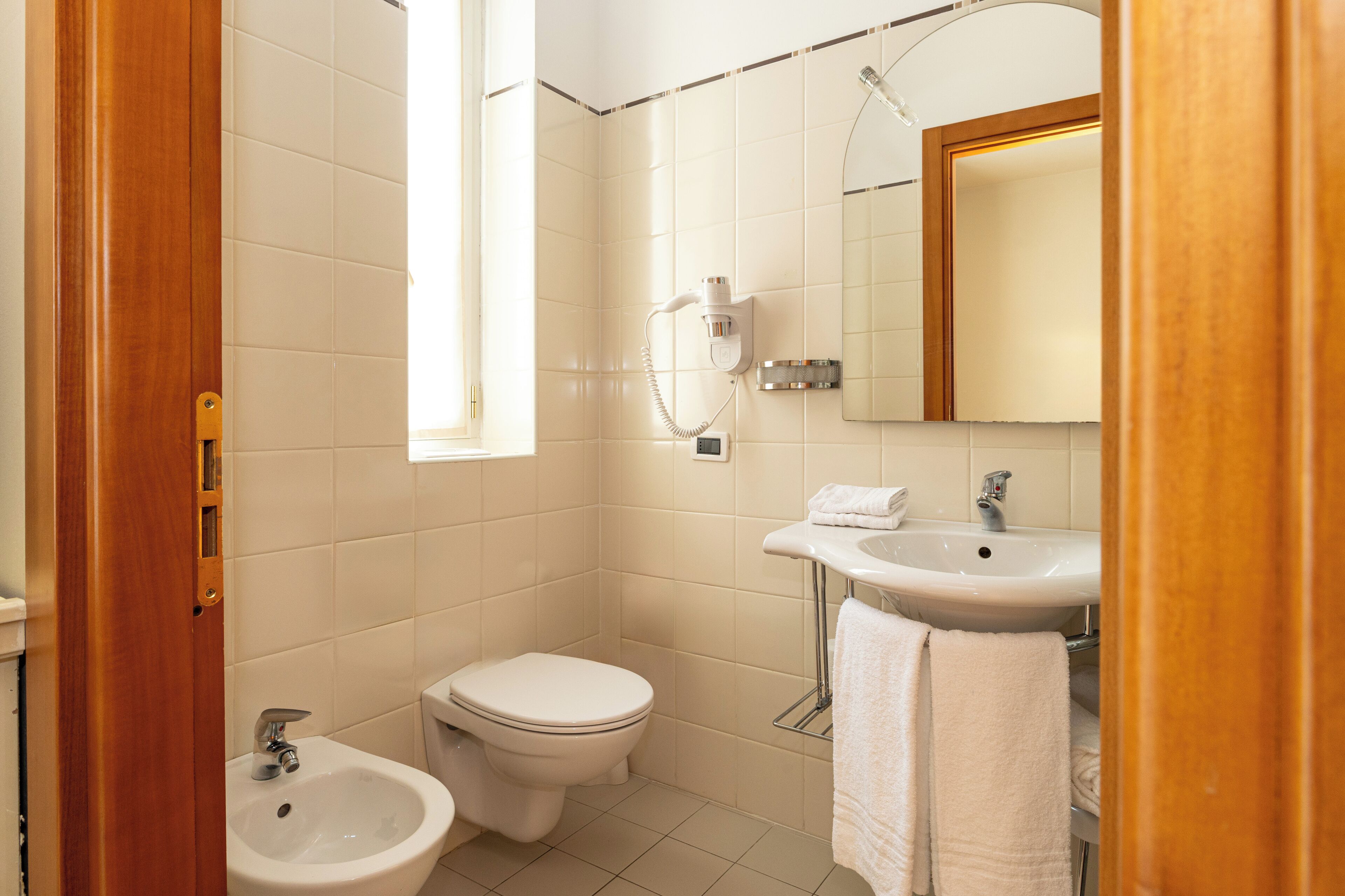 A bathroom with a toilet, bidet, sink, and mirror.