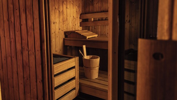 Una sauna de fusta amb una barra, un cubell i un llibre.