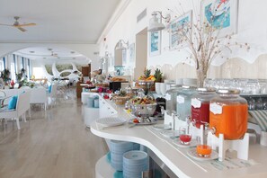 Un buffet proposant une variété de plats et de boissons, un ventilateur de plafond et des œuvres d’art accrochées aux murs.