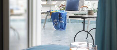 Un plateau de petit-déjeuner avec des toasts et du jus d’orange, posé sur un balcon d’où l’on peut admirer la piscine et les plantes en pot.
