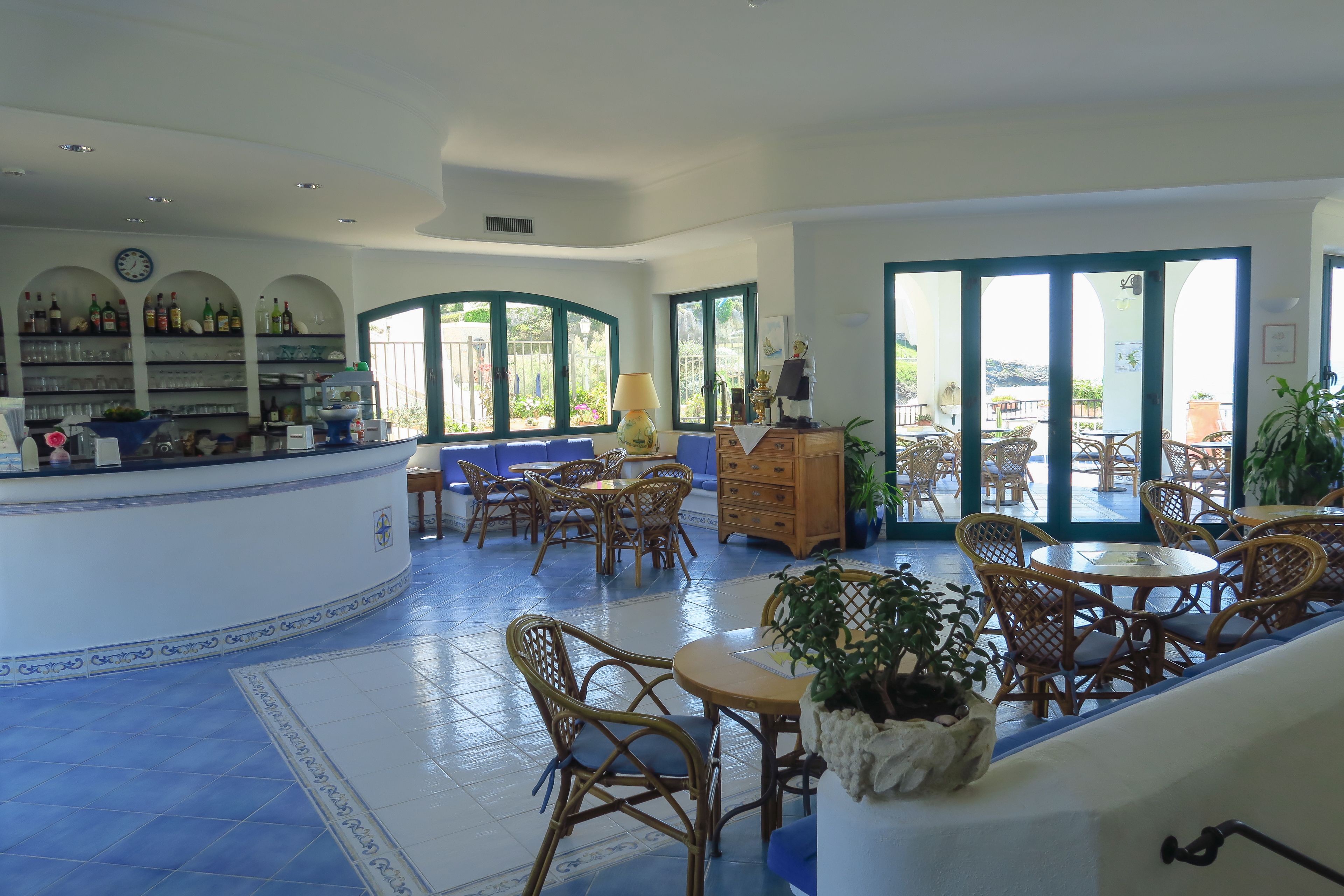 A spacious indoor area with a bar, wicker furniture, and large windows.
