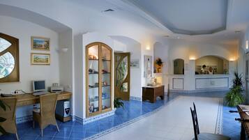 A spacious hotel lobby with a central seating area, a reception desk, and a large stained glass window.