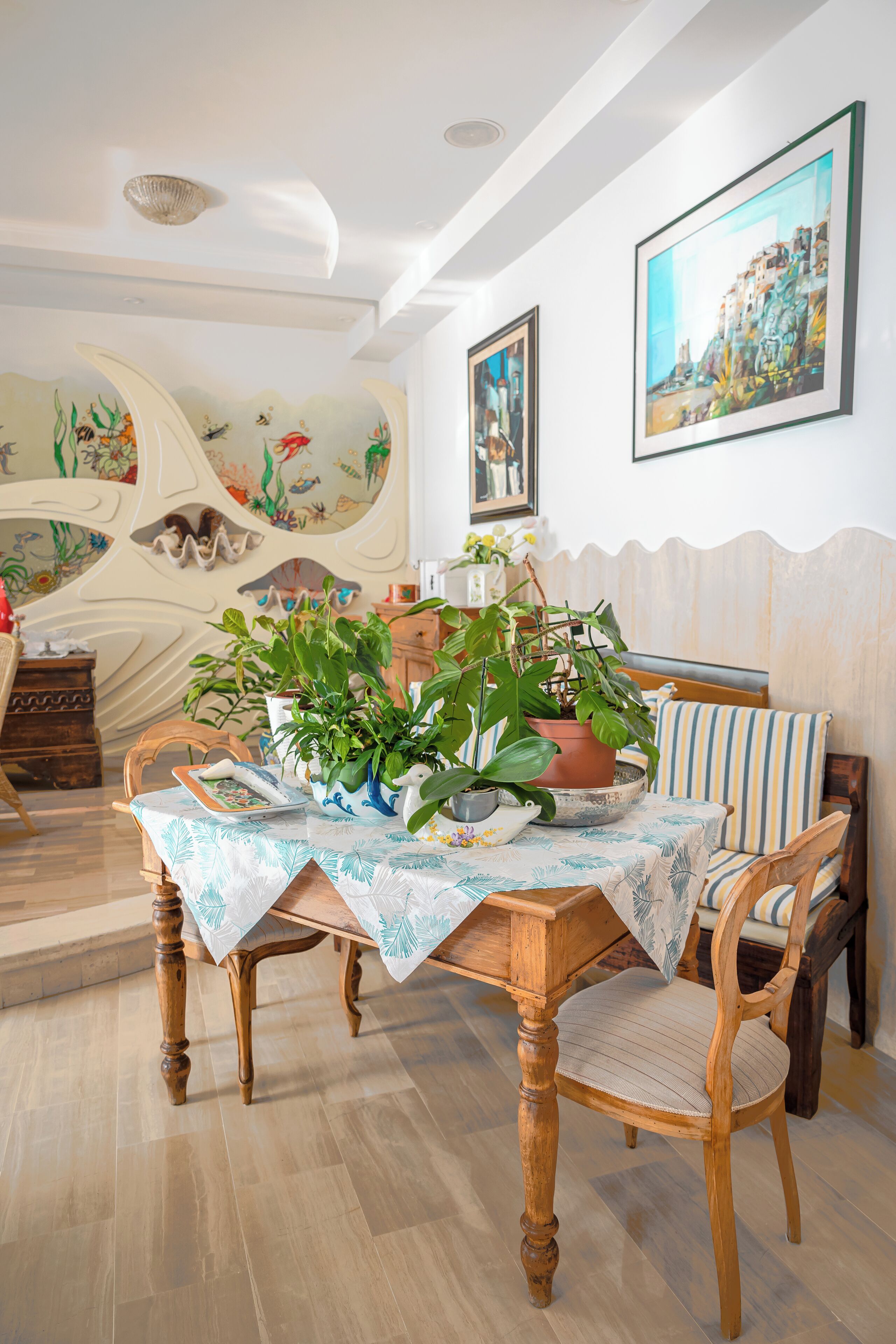A dining area with a wooden table, chairs, and potted plants.