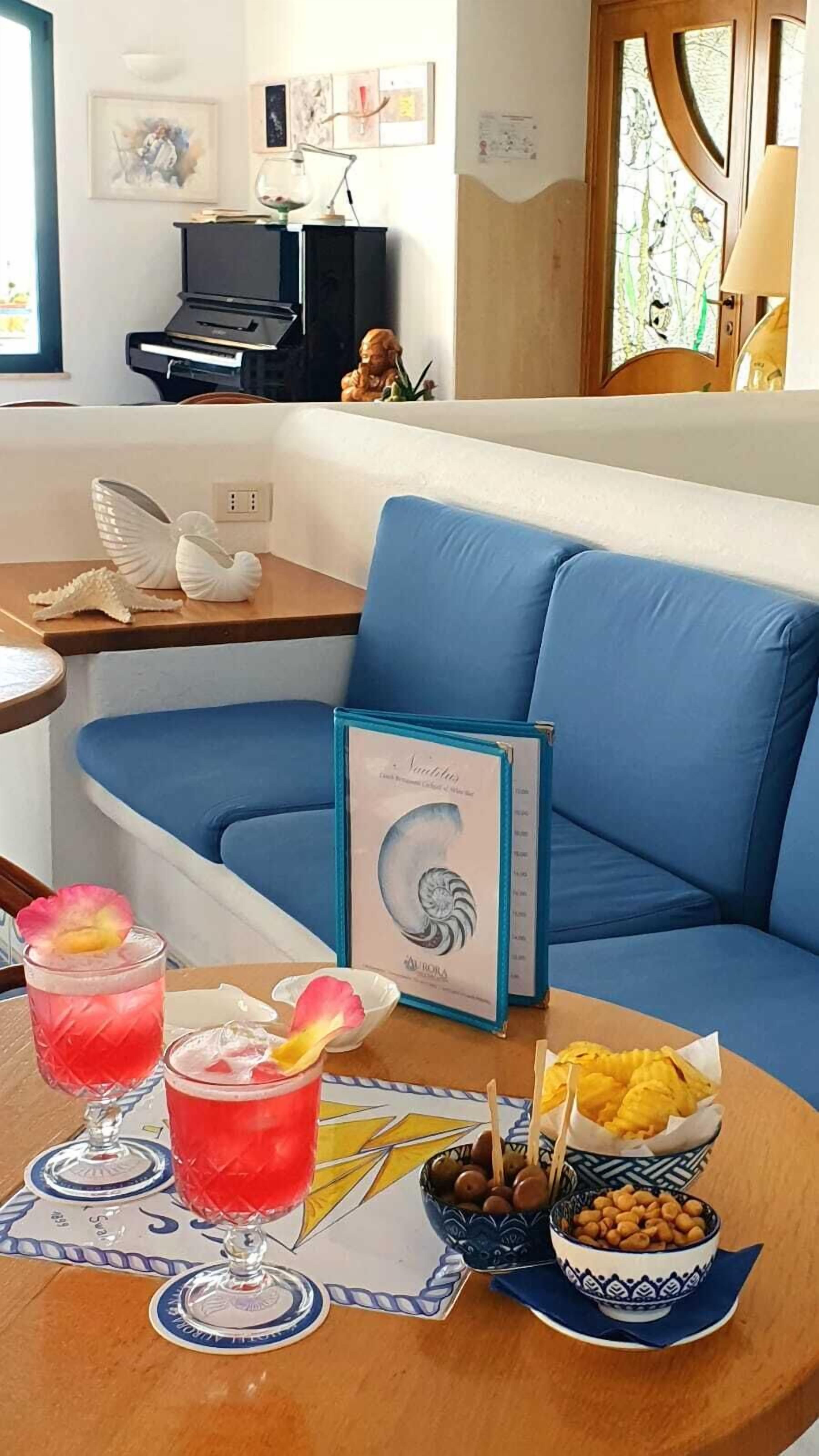 A room with a blue sofa, a table with drinks and snacks, and a framed picture on the wall.
