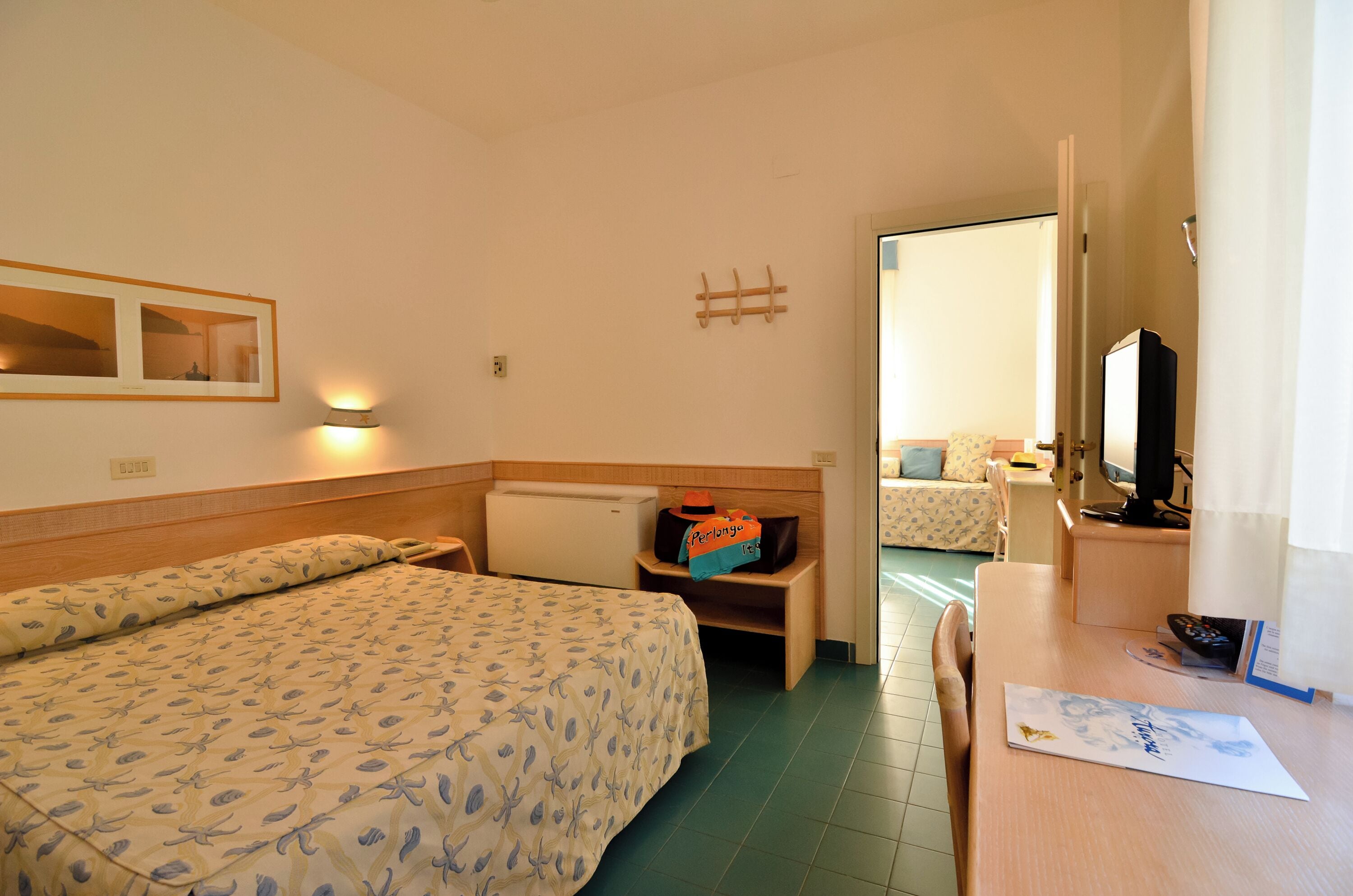 Una habitació d'hotel amb llit, escriptori, cadira, televisió i mirall.