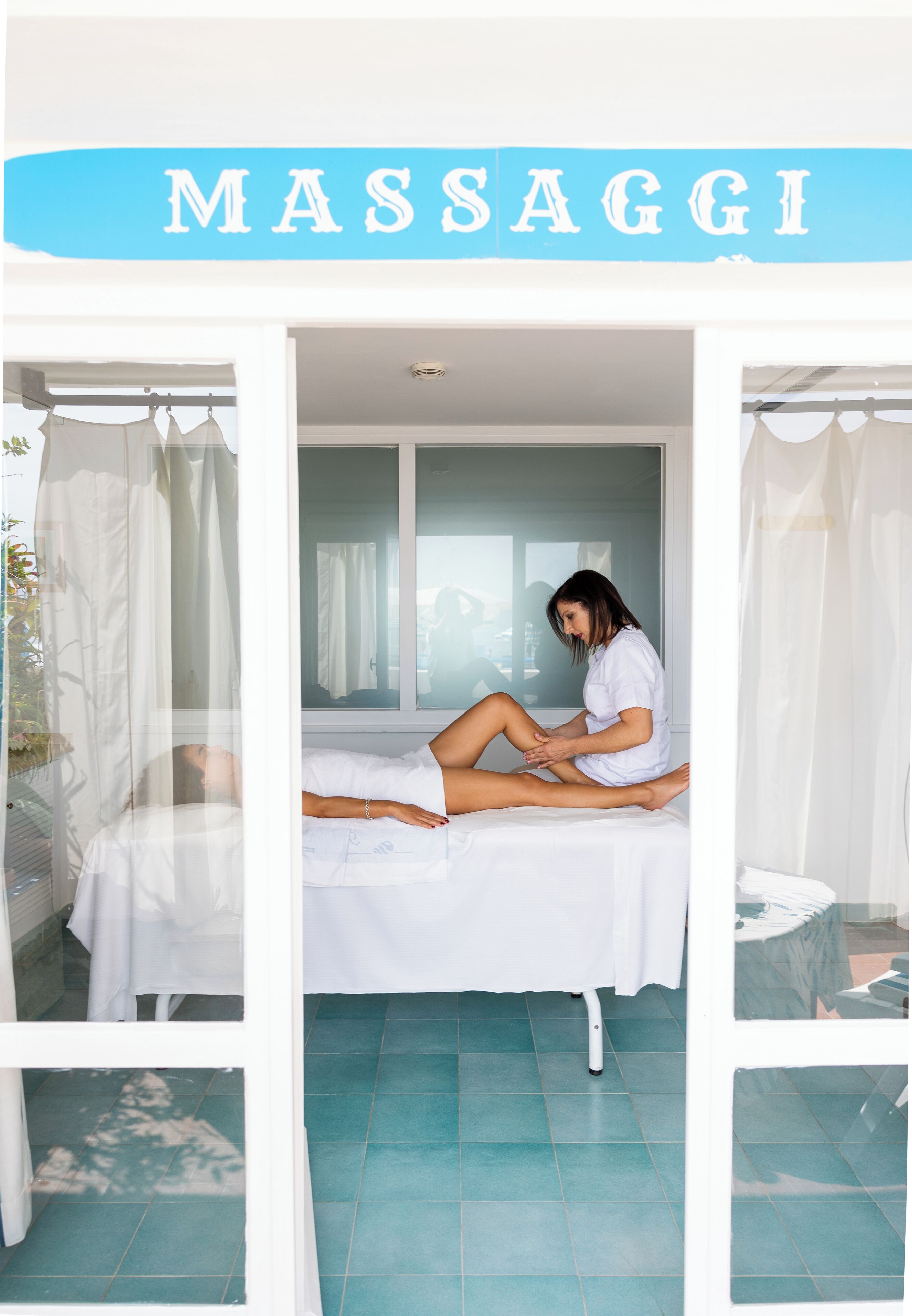 A massage room with a bed, a massage table, and a curtain.