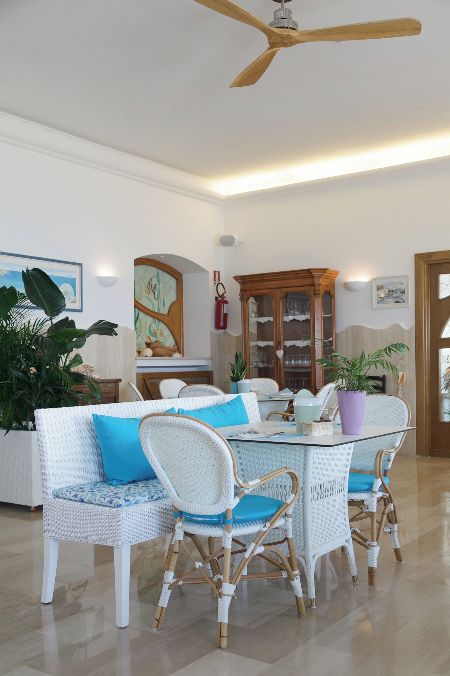 A dining area with wicker furniture, a ceiling fan, and a glass-top table.