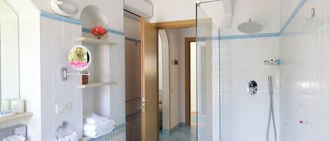 A modern bathroom with a glass-enclosed shower, white tiled walls, and a visible door leading to another room.