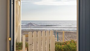 An arched doorway leading to a balcony with a view of the beach and ocean.