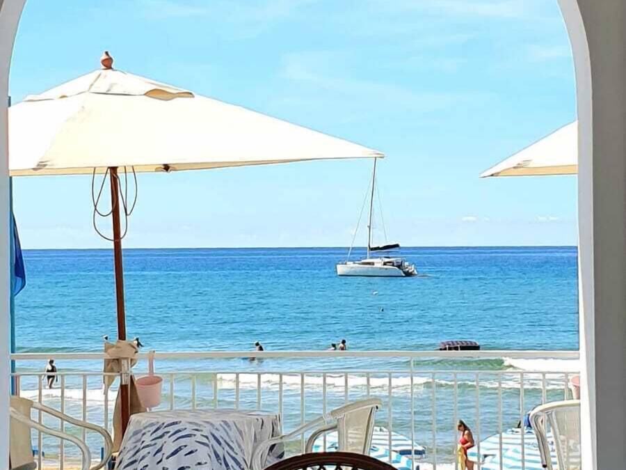 A seaside terrace with a table, chairs, and umbrellas overlooking the ocean.