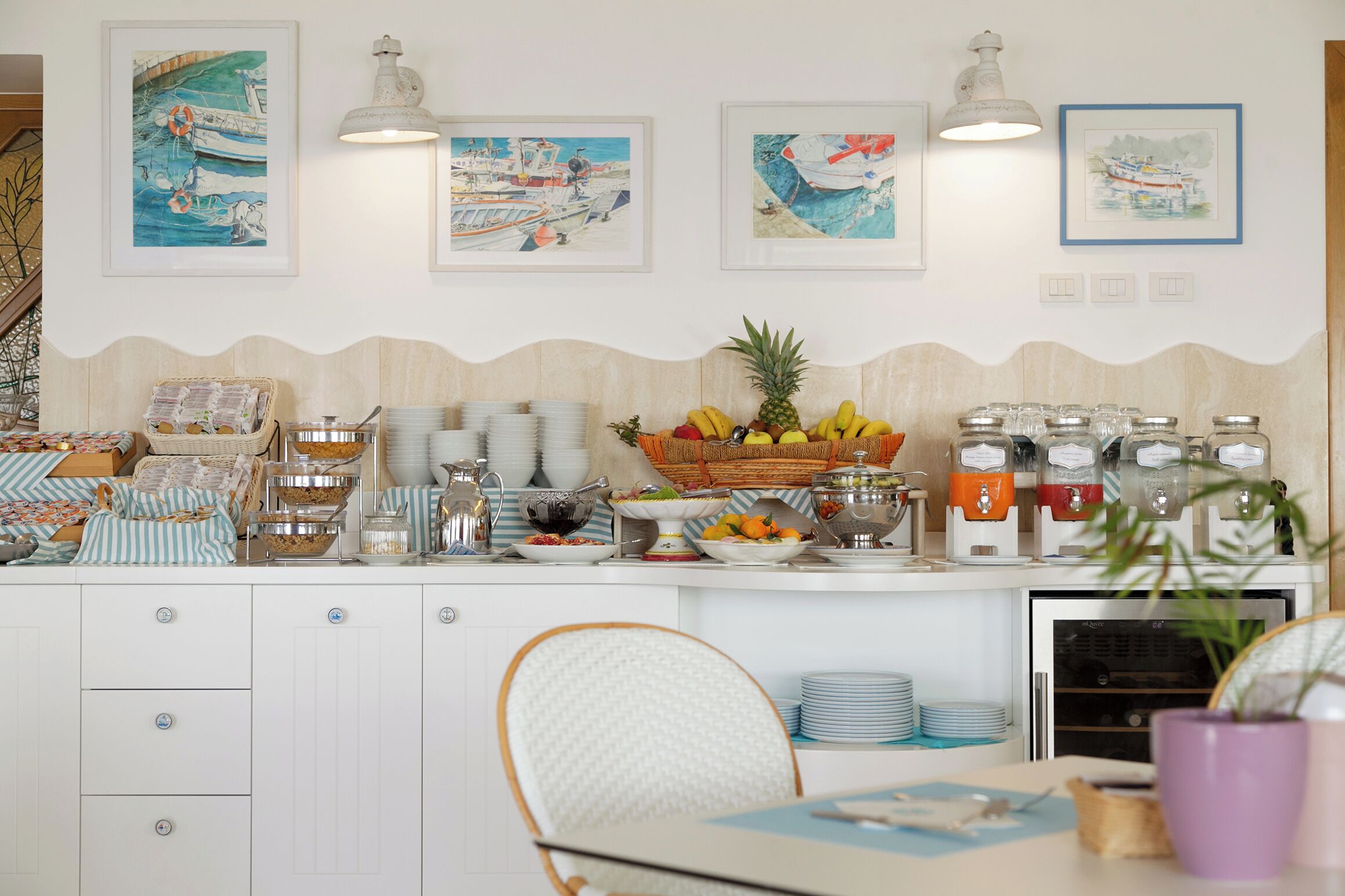 Un buffet de petit-déjeuner proposant une variété d’aliments, un coin café et des œuvres d’art murales représentant des bateaux.