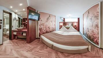 Une chambre moderne avec un grand lit, une télévision et une salle de bain équipée d’un meuble-lavabo et d’un évier.
