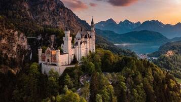 Eine Burg, umgeben von Wald und Bergen.