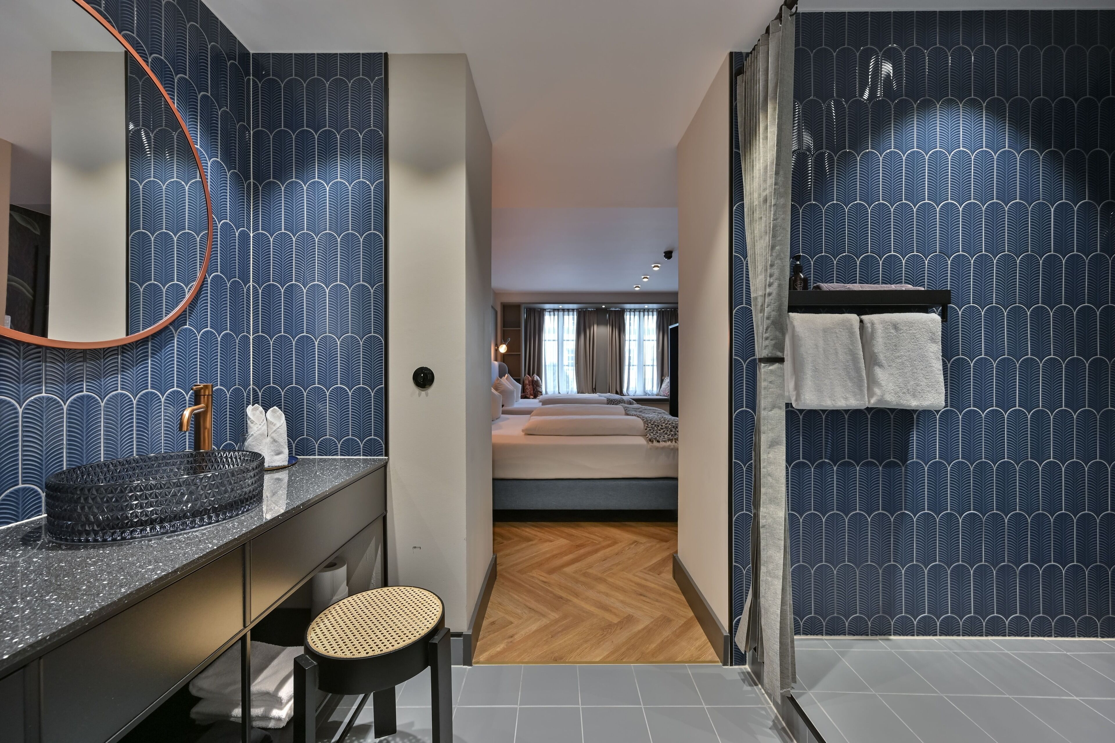 A modern bathroom with a large mirror, a black sink, and a wooden chair.