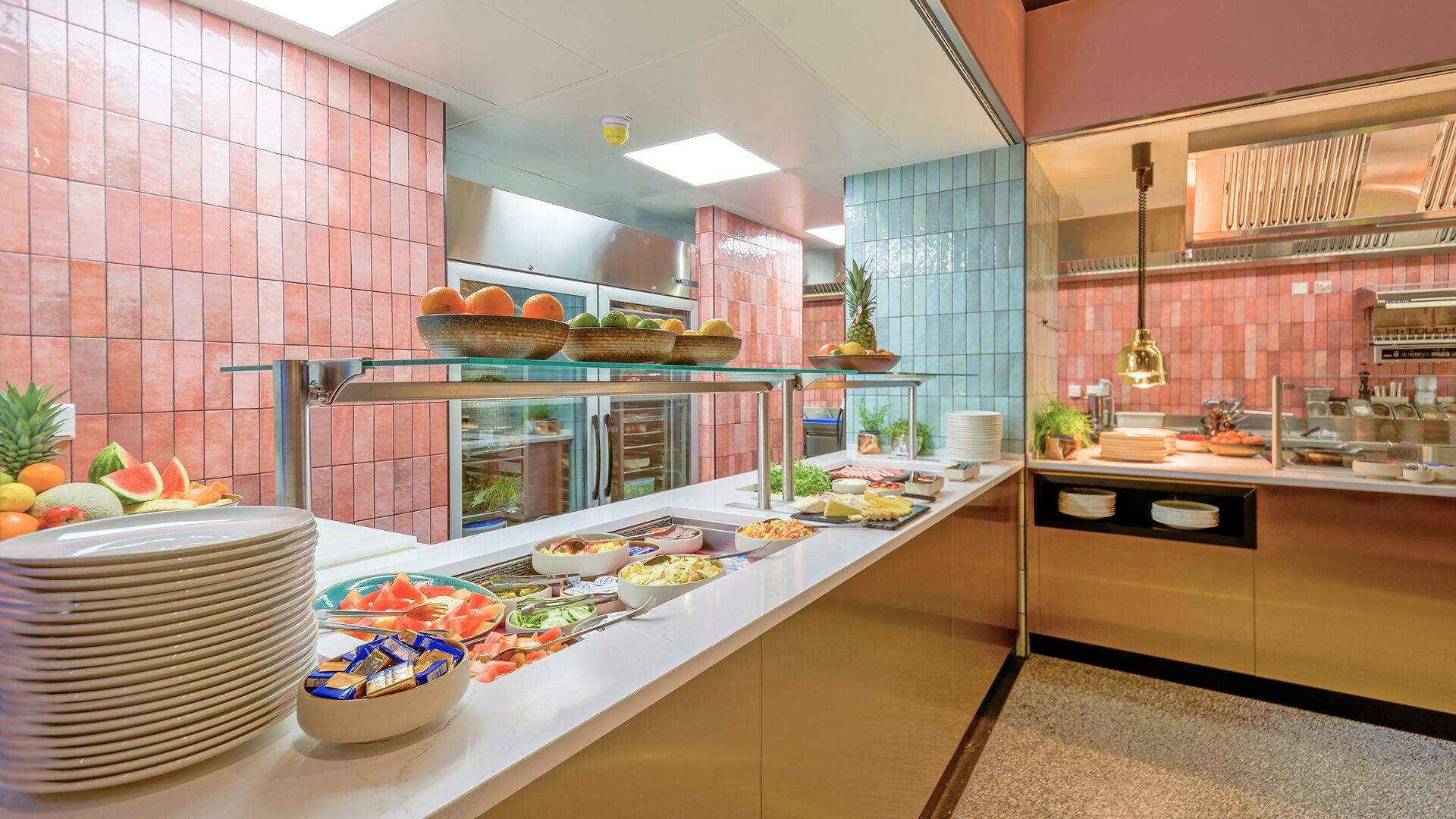 Un bufé con diversos alimentos y una vitrina de vidrio con frutas.