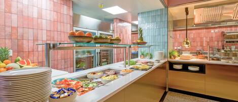 Un buffet proposant une variété de plats et une vitrine réfrigérée où sont exposés des fruits.