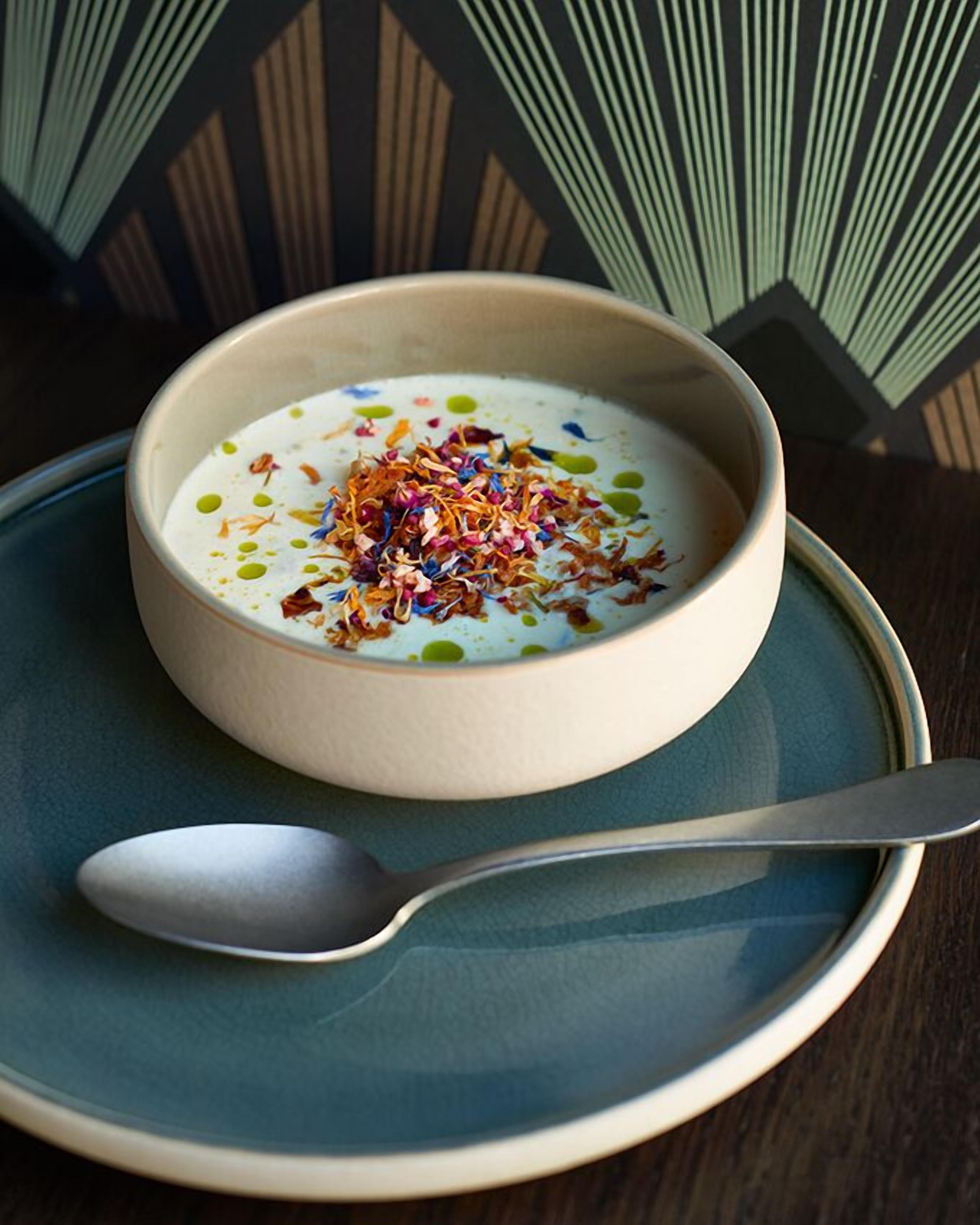 A bowl of soup with a spoon on a plate.