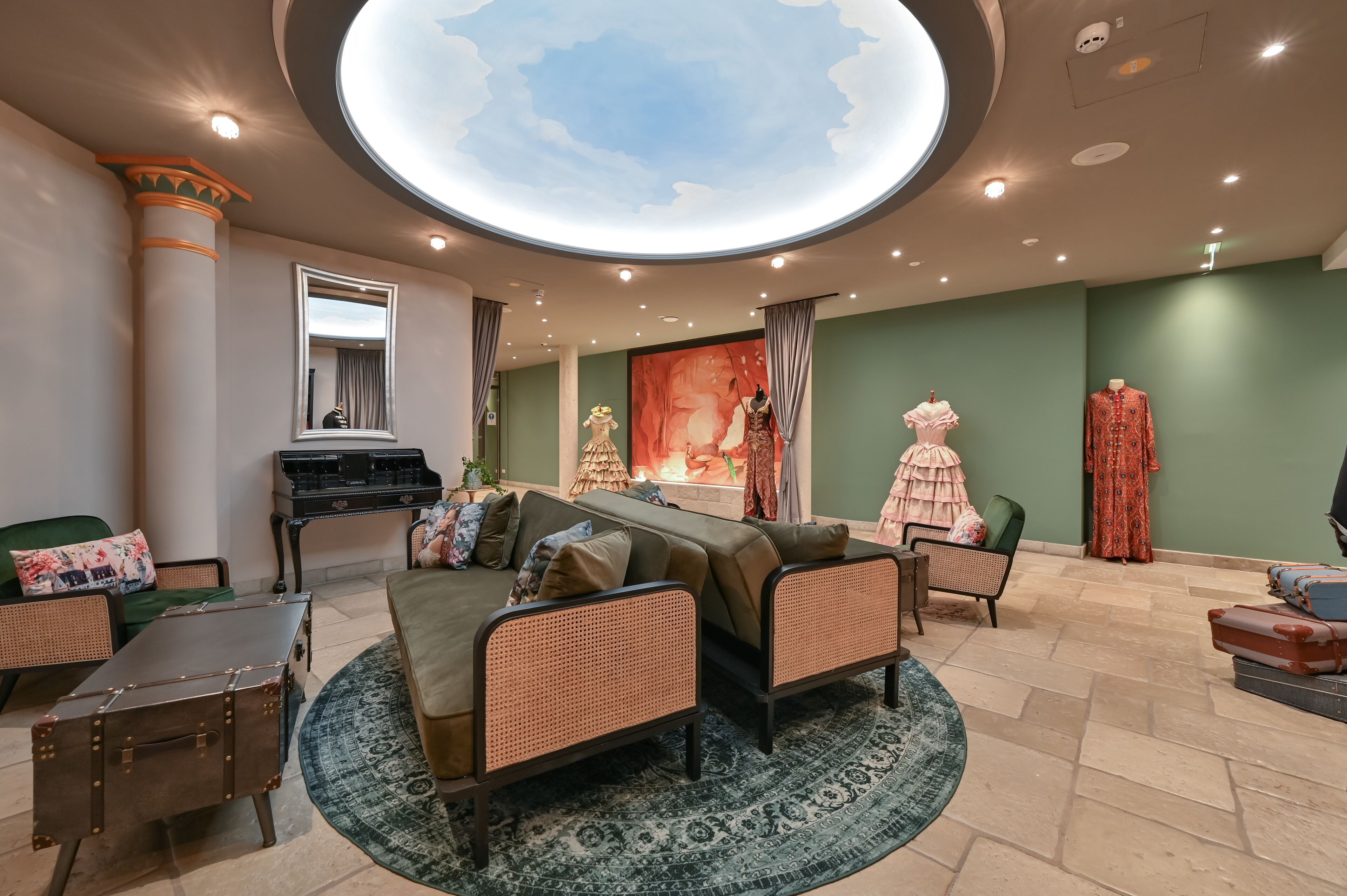 A spacious living room with a large round ceiling skylight, a fireplace, and a green sofa.