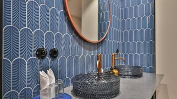 Une salle de bain avec un lavabo rond, un miroir et un porte-serviettes.