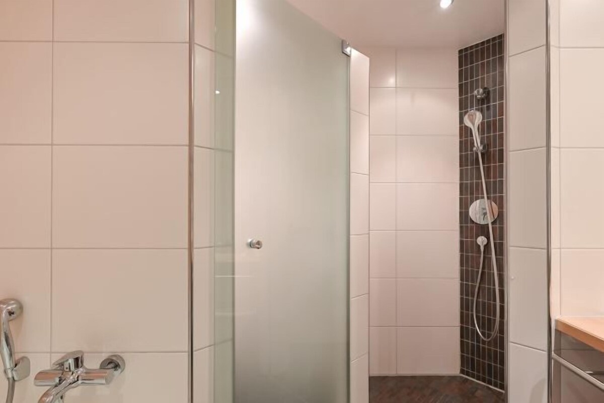 Un baño moderno con cabina de ducha de vidrio, ducha independiente y tocador con espejo.
