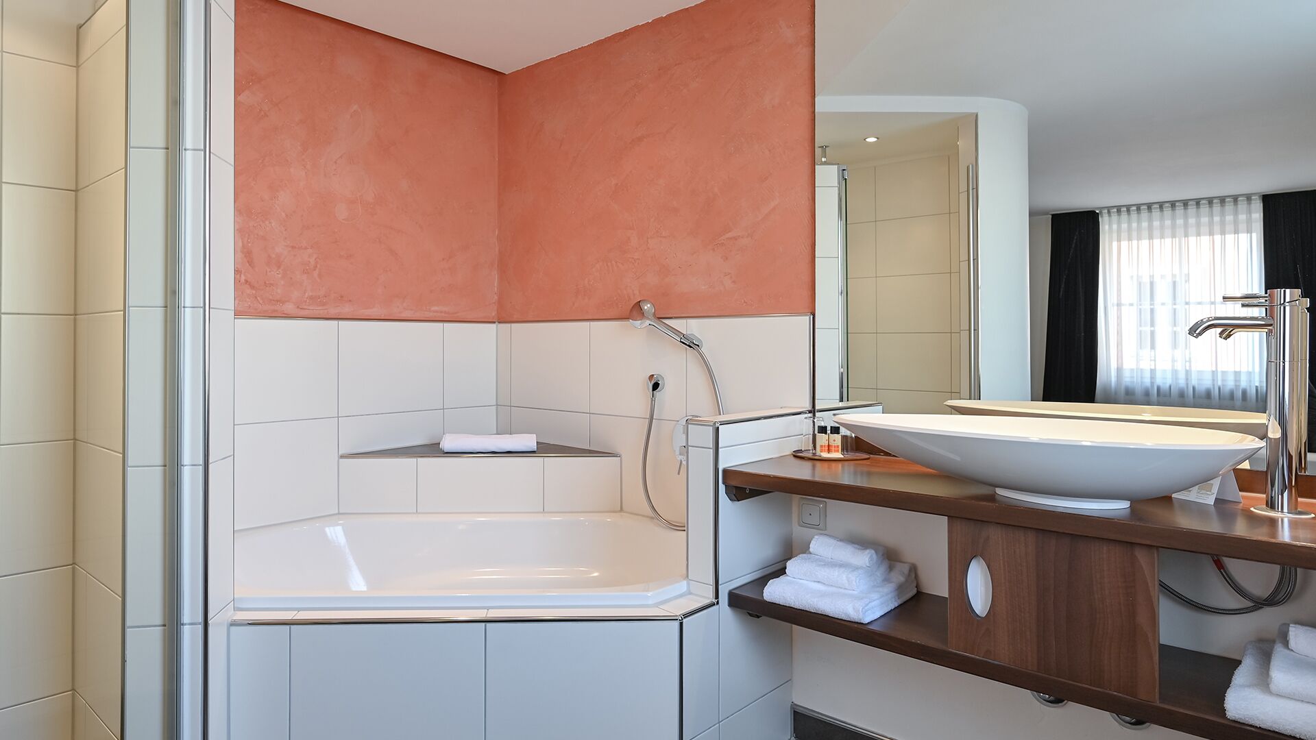 A modern bathroom with a bathtub, a large mirror, and a vanity with a sink.