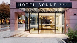 Una entrada de hotel moderna con fachada de vidrio y un letrero que dice 'HOTEL SONNE'.