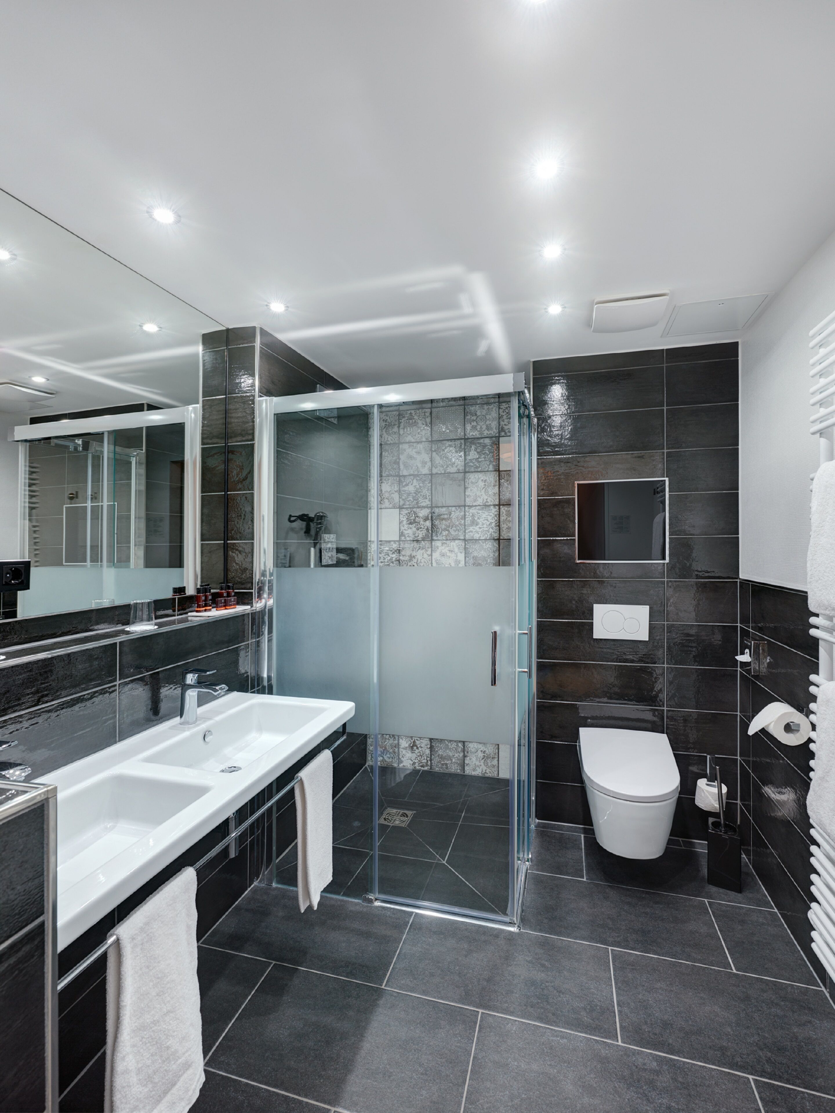 Une salle de bain moderne avec une douche à parois de verre, un lavabo blanc et des toilettes.