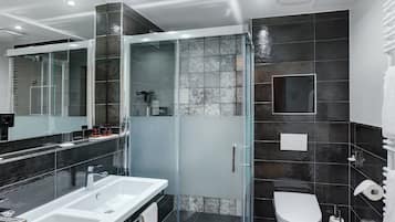Un baño moderno con ducha de vidrio, lavamanos blanco y un inodoro.