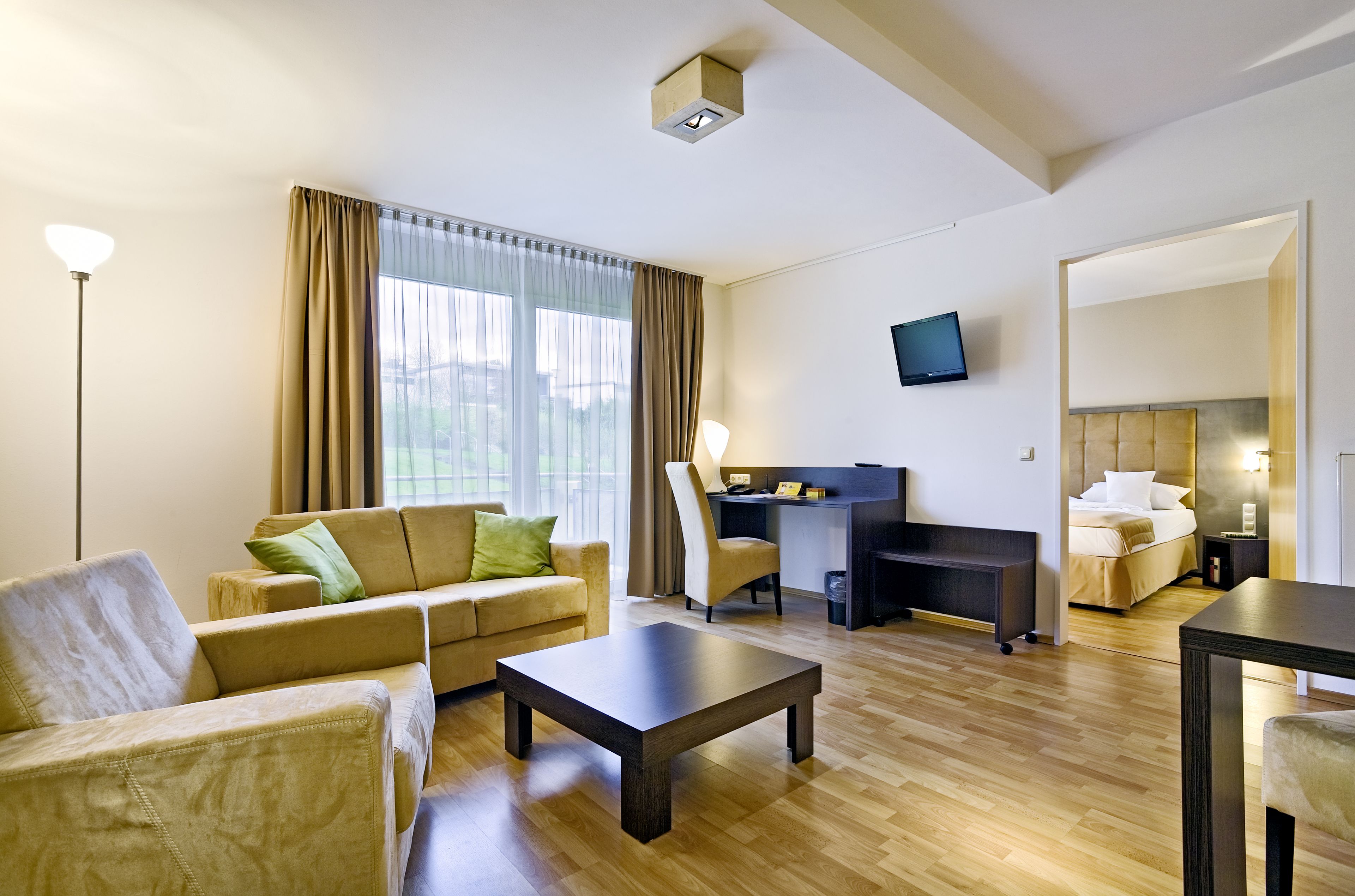 Una habitación de hotel moderna con sofá, mesa de centro, escritorio y cama.