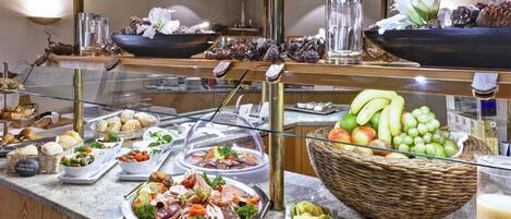 Un bufé con diversas opciones de comida, incluyendo pastelería, frutas y ensaladas.