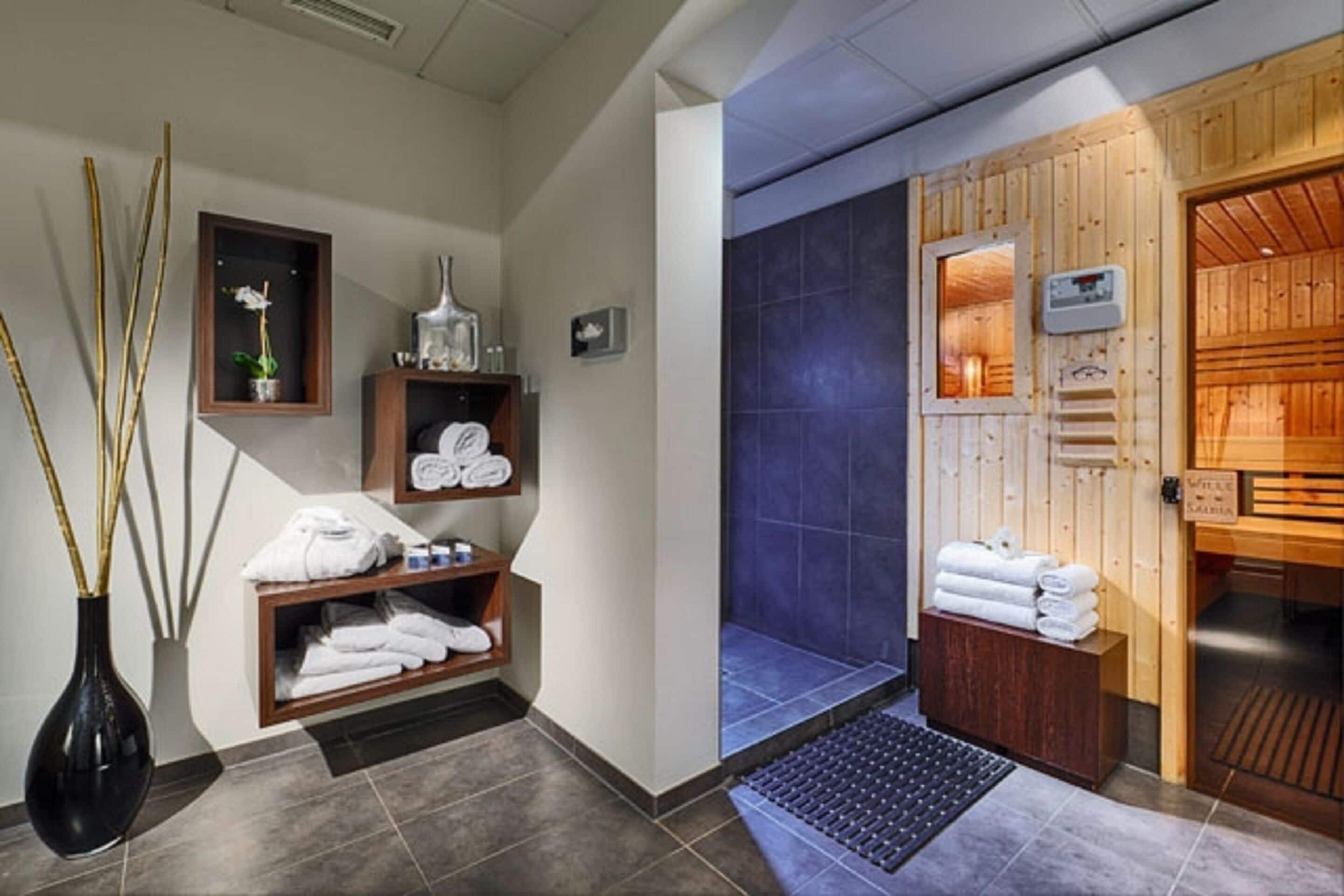 Un área de spa con paredes de madera, una ducha con azulejos azules y toallas ordenadas.
