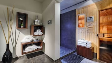 Un área de spa con paredes de madera, una ducha con azulejos azules y toallas ordenadas.