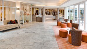 A spacious lobby with a reception desk, seating area, and large windows.