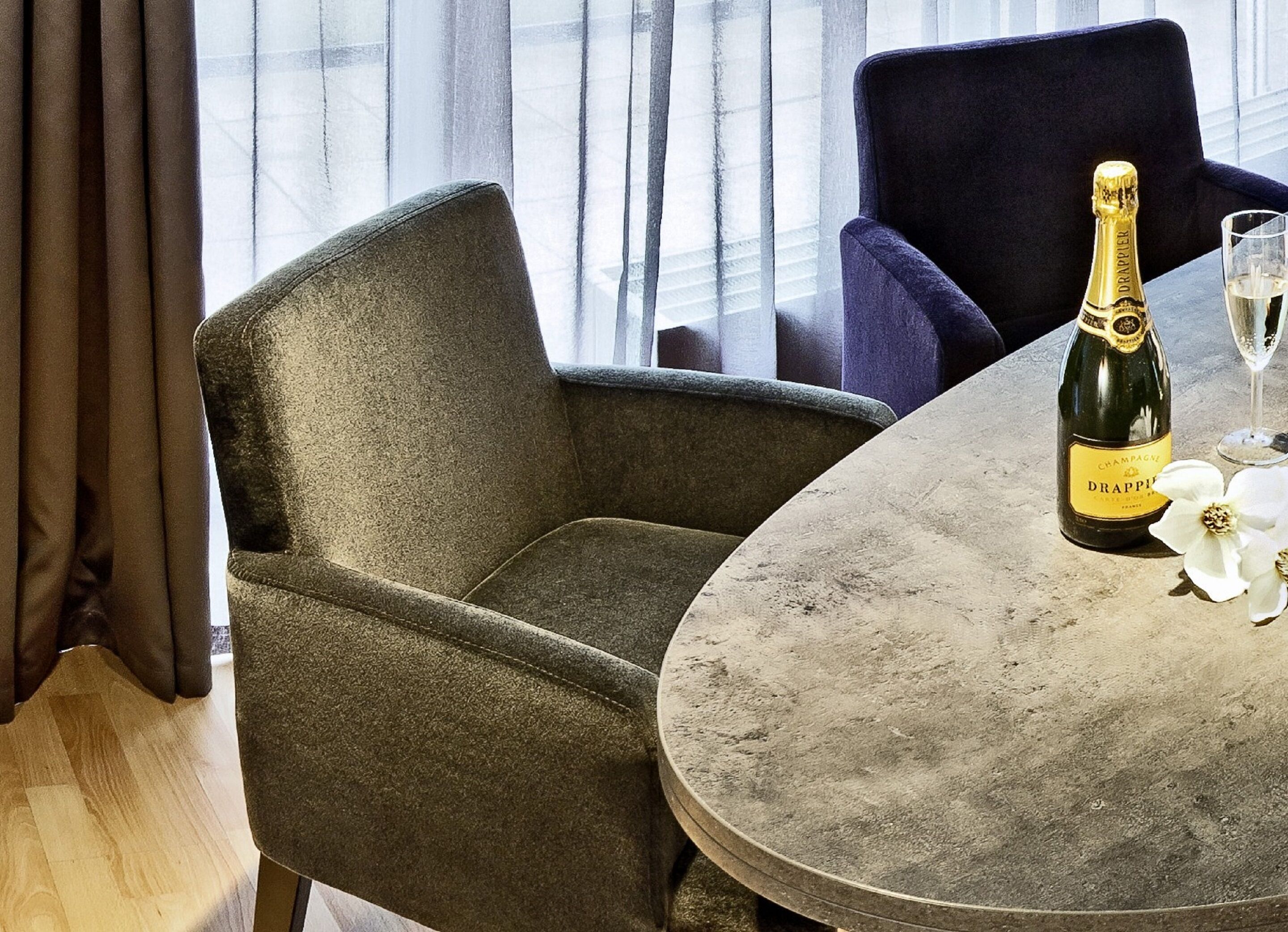 Et værelse med et rundt bord, en champagneflaske og et glas på bordet.