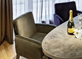 Una habitación con una mesa redonda, una botella de champán y una copa encima.