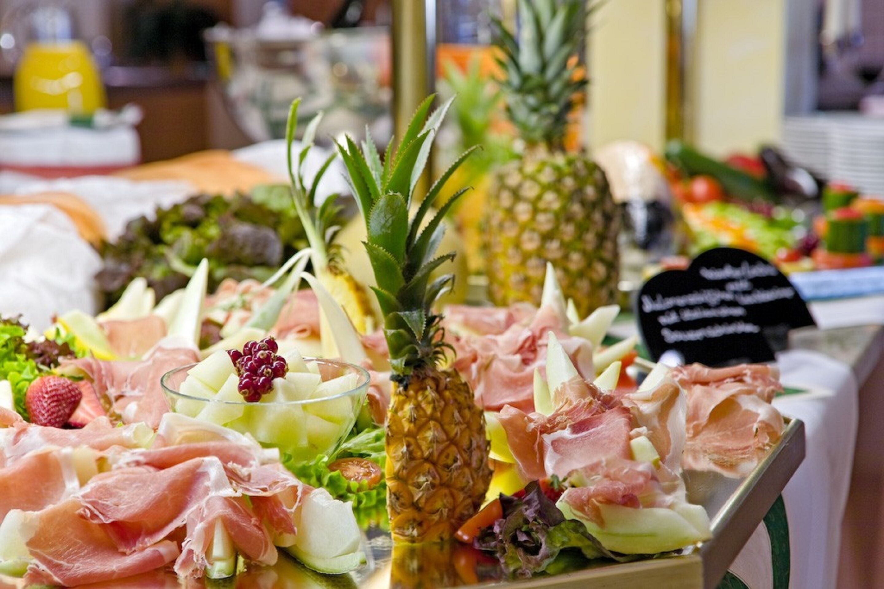 A buffet with various food items including meats, fruits, and salads.
