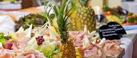 A buffet with various food items including meats, fruits, and salads.