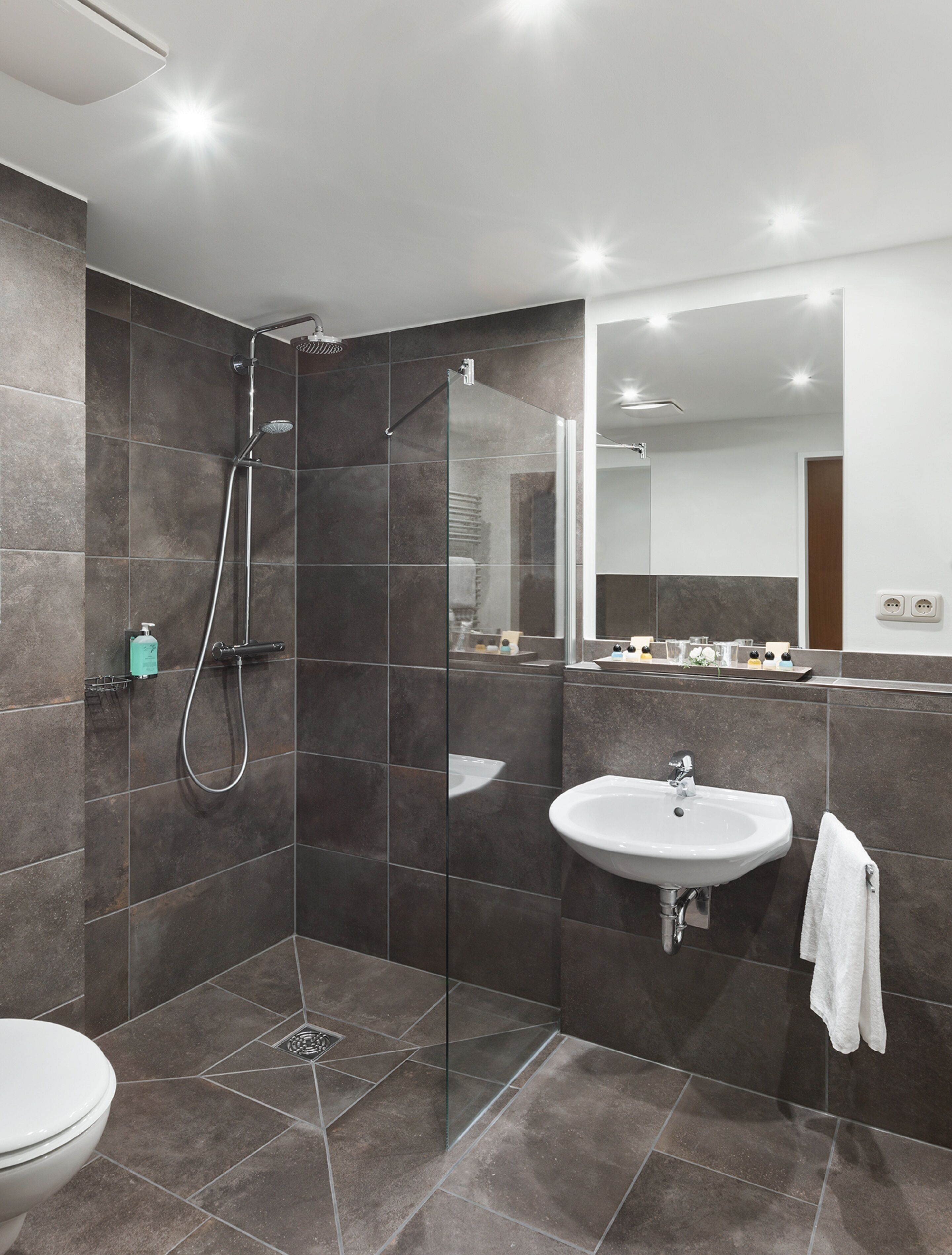 A modern bathroom with a glass-enclosed shower, a white sink, and a toilet.