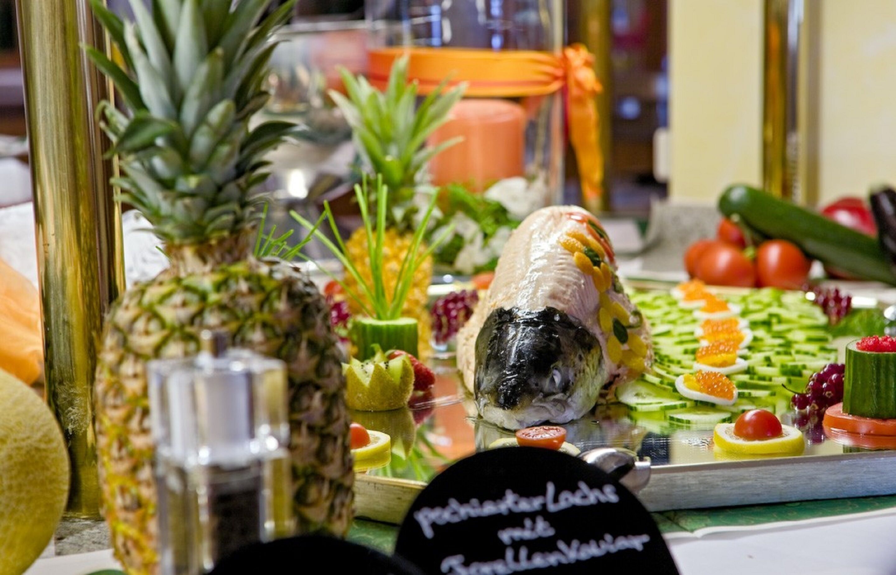 A buffet with various fruits and vegetables, including pineapple, cucumber, and tomatoes.