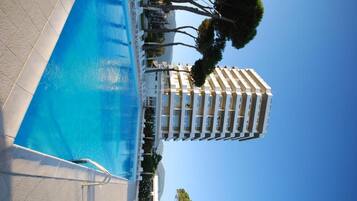 A swimming pool adjacent to a hotel with a clear blue sky.