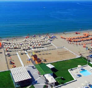 A beach resort with a circular seating area, a pool, and a building with a sloped roof. - Hotel Torre Del Sole (Terracina)